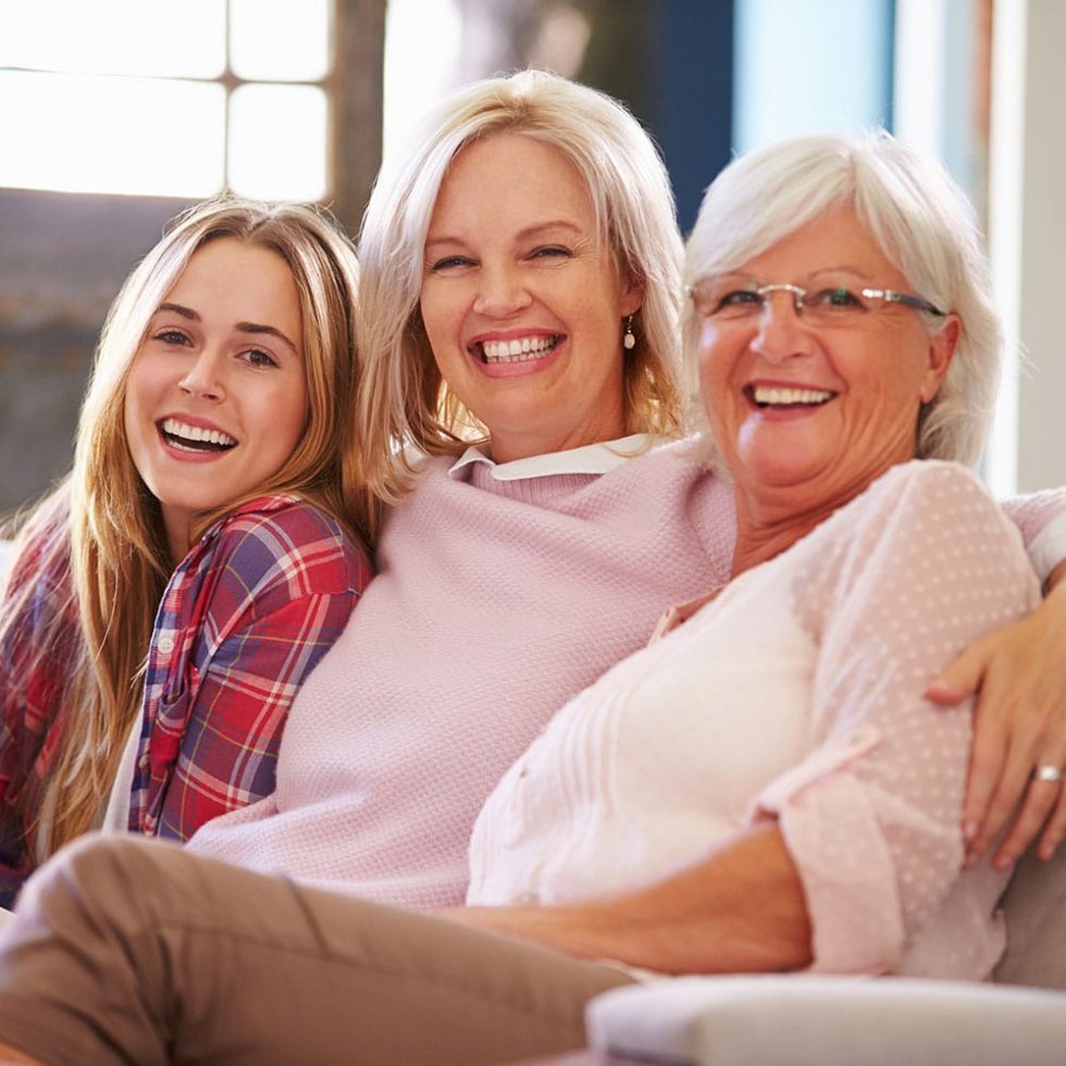Grandmother With Mother And Adult Daughter Relaxing On Sofa