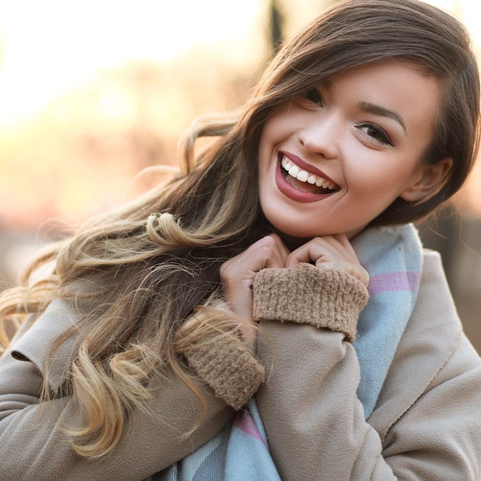 Young lady smiling brightly in order to see her white teeth.